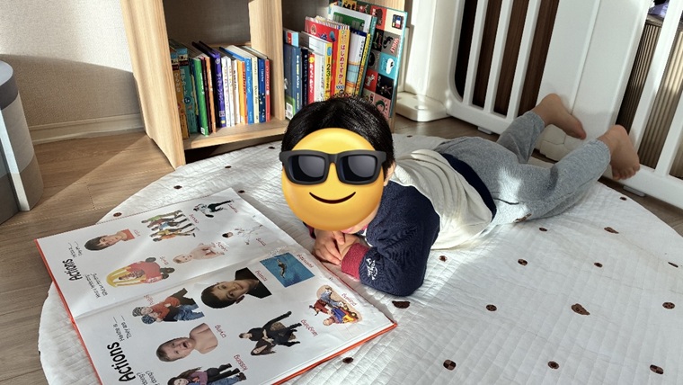 絵本棚の前で本を読む男の子