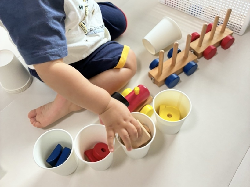 棒とおしと紙コップで遊んでいる子供